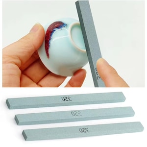 Puede incluir: Tres piedras de afilar grises con el número 320 impreso en cada una. Las piedras son rectangulares y tienen una textura rugosa.