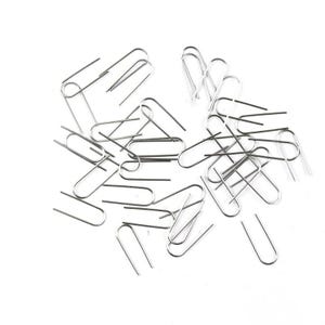 Peut inclure: Un ensemble d'agrafes argentées éparpillées sur un fond blanc. Les trombones sont faits de fil métallique fin et ont un design classique en fil plié. Les clips sont dans différentes orientations.