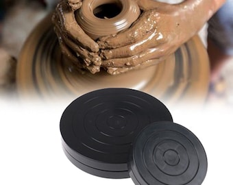 May include: Two black pottery wheels, one larger than the other, with concentric circles on the surface. The wheels are used for pottery making.