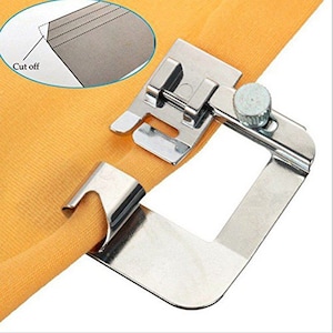 Puede incluir: Un pie de máquina de coser plateado con una guía de tela y una perilla para ajustar el ancho del dobladillo. El pie está unido a un trozo de tela naranja.