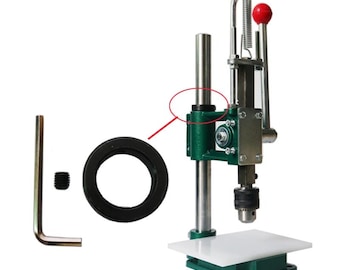 May include: A green metal press with a white platform, a black ring, a silver wrench, and a small silver screw. The press has a silver rod with a black ring at the top.