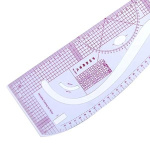 May include: A clear, versatile cutting-out ruler with purple grid lines and measurements in centimeters. The ruler features curved edges, a circular protractor, and text in Chinese. It is designed for sewing and pattern making.