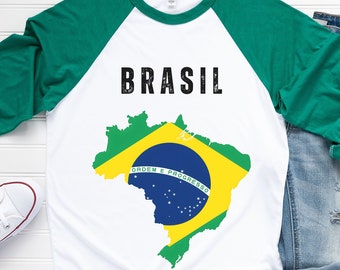 May include: A white t-shirt with green sleeves and the word "BRASIL" printed in black on the front. The shirt also features a graphic of the Brazilian flag in the shape of the country's outline.