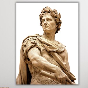 May include: A close-up of a marble statue of a Roman emperor wearing a laurel wreath. The statue is in a light brown colour and is set against a white background.