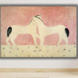 Op de afbeelding: Een rechthoekige wandkunstprint met twee crèmekleurige paarden met zwarte staarten, staand op een lichtbeige ondergrond tegen een roze, getextureerde achtergrond. Het onderste deel van het kunstwerk toont kleine, verspreide donkere symbolen.