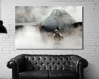 May include: A rectangular wall art print featuring a gray fighter jet surrounded by thick white steam or smoke. A figure wearing a helmet and gear stands in front of the aircraft. The number 75 is visible on the side of the jet fuselage.
