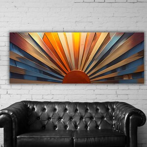 Op de afbeelding: Een rechthoekig wandkunstwerk met een gestileerd zonnestraalontwerp met een effen donkeroranje halve cirkel in het midden onderaan. Afwisselende panelen in heldergeel, oranje, beige en gedempte blauwtinten stralen in een waaierpatroon uit.