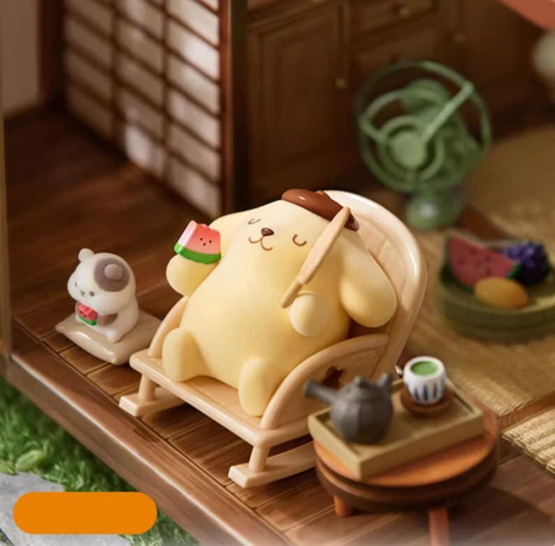 K&ouml;nnte beinhalten: Eine Miniatur-Diorama-Szene mit einer gelben Cartoon-Hundefigur, die sich in einem Schaukelstuhl entspannt und eine Wassermelone h&auml;lt. Eine kleine Hundefigur sitzt in der N&auml;he. Ein Miniatur-Teeservice und ein Ventilator sind ebenfalls vorhanden.