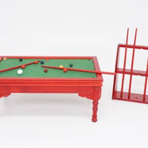Peut inclure: Un billard miniature en bois rouge avec un tapis de jeu vert et un jeu de boules colorées. La table a un support pour tenir les queues.