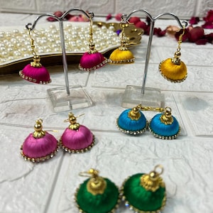 May include: A set of six colorful silk thread earrings with gold accents and clear rhinestone embellishments. The earrings are displayed on a stand.
