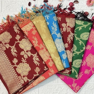 May include: A collection of colorful scarves with floral patterns. The scarves are in shades of red, gold, blue, green, and pink, with gold floral designs. Each scarf has a fringed edge.