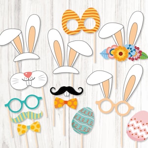 May include: A set of 10 Easter-themed photo booth props, including bunny ears, a moustache, glasses, a bow tie, and eggs. The props are printed on white cardstock and have colourful designs.