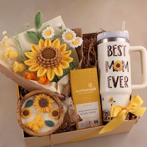 May include: A white ceramic mug with a black handle and the text "But First, Coffee" in a black, handwritten-style font. The mug is on a white surface.