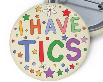 May include: A round button with a cream background and colorful text that reads "I HAVE TICS". The text is surrounded by small stars and flowers.