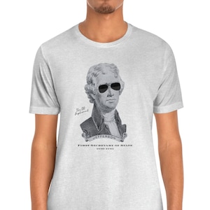 May include: A gray t-shirt with a graphic of Thomas Jefferson wearing sunglasses and the text "First Secretary of State 1790-1793".