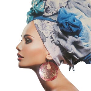 Puede incluir: Perfil de una persona que lleva pendientes de aro grandes, texturizados, rojos y dorados. La persona también lleva un pañuelo en la cabeza con diseños azules y blancos.