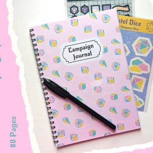 May include: A pink spiral bound journal with a dice pattern and the words "Campaign Journal" on the cover. The journal is accompanied by a sheet of pastel dice stickers.