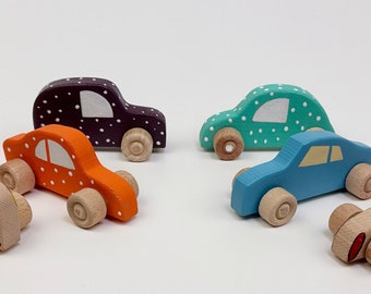 May include: Set of six wooden toy cars with polka dot designs in various colors, including orange, purple, blue, green, and red. The cars have wooden wheels and are painted with white polka dots.