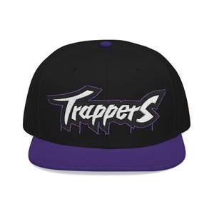 Könnte beinhalten: Schwarze und lila Baseballkappe mit dem Wort "Trappers" in Weiß, umrandet von Lila. Die Kappe hat einen flachen Schirm und einen Knopf oben. Ein modisches Accessoire.
