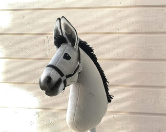 May include: A gray and black stuffed horse head on a stick. The horse has a black bridle and a black mane.