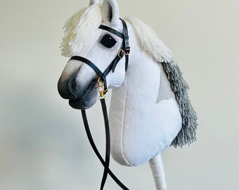 May include: A white plush rocking horse with a gray mane and tail. The horse has a black leather bridle with a gold buckle and a black leather rein.