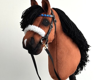May include: Brown and black hobby horse with a black mane and tail, white nose band, black leather bridle with a blue jeweled browband, and a black lead rope.