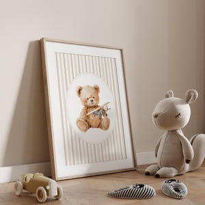 May include: A framed print featuring a watercolor illustration of a teddy bear holding a toy airplane. The artwork is set against a striped background in a neutral color palette. A wooden toy car and a stuffed squirrel are in the foreground.
