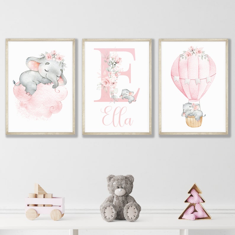 May include: Three pink and gray nursery prints featuring a sleeping elephant on a cloud, a hot air balloon with elephants, and a floral letter E with the name Ella.