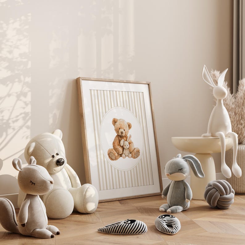 May include: A framed print of a teddy bear holding a bunny, surrounded by plush toys. A white ceramic rabbit sits on a small table. Other toys include a gray bunny, a gray knot, and two black and white striped objects.