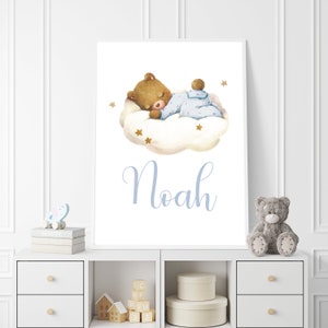 Op de afbeelding: Een aquarel-illustratie van een bruine teddybeer die slaapt op een witte wolk met gouden sterren. De beer draagt een blauw-wit gestreepte romper. De naam "Noah" staat in blauwe cursieve letters onder de wolk.