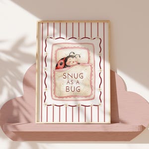 Unframed Snug as a Bug nursery wall art print featuring a sleeping ladybird illustration in soft pink tones for baby girl nursery decor.