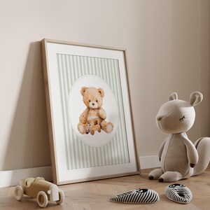 May include: A framed print featuring a watercolor illustration of a teddy bear holding a wooden toy train. The background has vertical stripes in light green and white. A stuffed squirrel and toy car are on the floor.