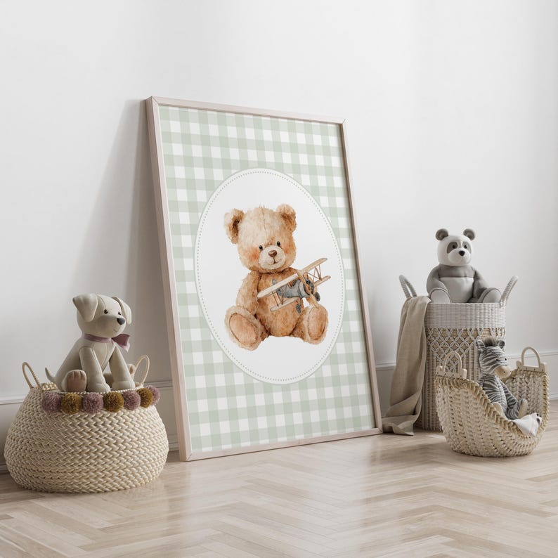 May include: A framed print featuring a watercolor illustration of a teddy bear holding a toy airplane. The background is a light green and white gingham pattern. Wicker baskets with stuffed animals are in the foreground.