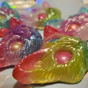 May include: A group of five small, colorful, resin cat figurines with iridescent glitter and pearl accents. Each figurine has a different color scheme, including pink, blue, green, and purple.