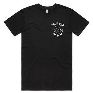 May include: Black t-shirt with a white graphic of crossed golf clubs and the text "Golf Dad" with the initials "S & M" underneath.