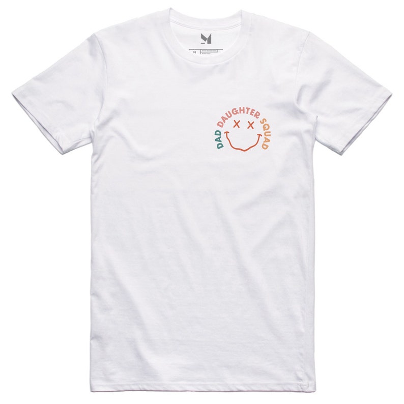May include: White t-shirt with a green, orange, and pink smiley face graphic that says "Dad Daughter Squad" around the face.