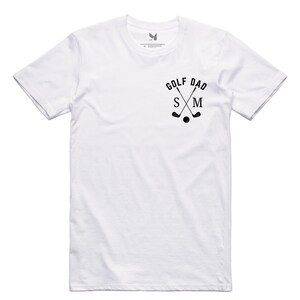 May include: White t-shirt with a black graphic of crossed golf clubs and the text "Golf Dad" with the letters "S" and "M" in the middle.