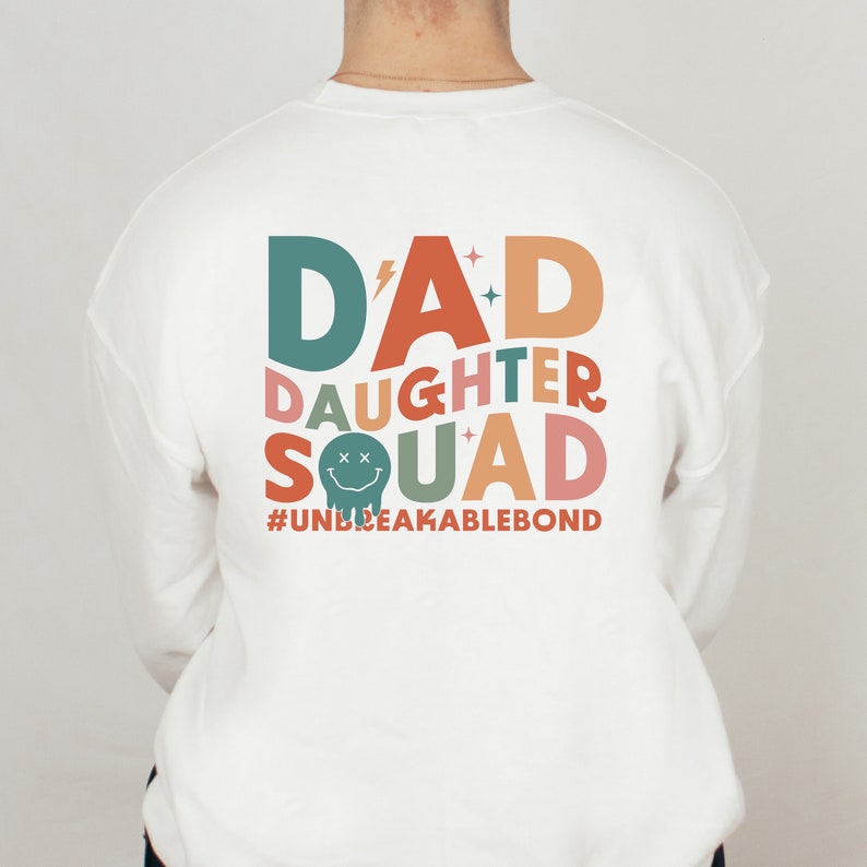 May include: White sweatshirt with a colorful graphic design that says "D'AD DAUGHTER SQUAD #UNBREAKABLEBOND".