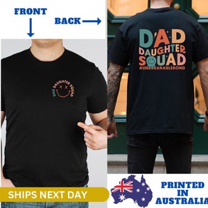 May include: Black t-shirt with a colorful graphic on the back that says "Dad Daughter Squad #UnbreakableBond". The front of the shirt has a smaller version of the graphic.