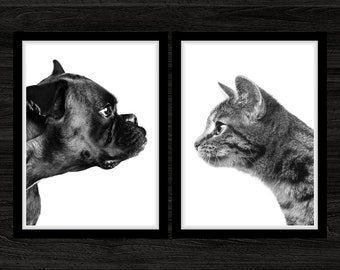 May include: Black and white framed art print set featuring a Boxer dog and a tabby cat, each in profile, facing each other. The artwork is set against a white background, with a black frame. The overall theme is pets and animal art.