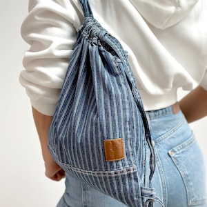 mini frayed denim blue stripe drawstring bag, on the women's shoulder