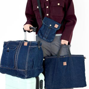 May include: A set of dark blue denim travel bags, including a tote, a crossbody bag, and a duffel bag, with brown leather tags. The bags are made of denim material. The bags are on top of a light green suitcase.