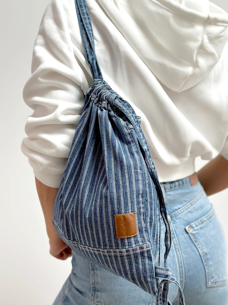 mini frayed denim blue stripe drawstring bag, on the women's shoulder