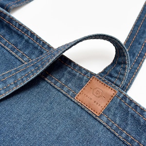 May include: A blue denim tote bag with a brown leather patch that says "Denim Deko" and a stylized "D" logo.