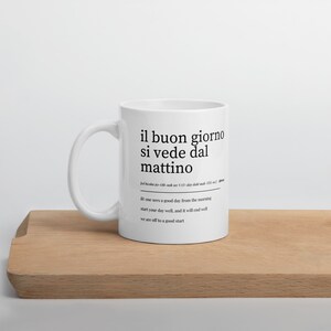 Puede incluir: Taza de cer&aacute;mica blanca con un dise&ntilde;o negro que dice "il buon giorno si vede dal mattino" en italiano, que se traduce como "un buen d&iacute;a se ve desde la ma&ntilde;ana". El texto tambi&eacute;n incluye la definici&oacute;n: "uno ve un buen d&iacute;a desde la ma&ntilde;ana comienza bien tu d&iacute;a, y terminar&aacute; bien vamos a un buen comienzo."