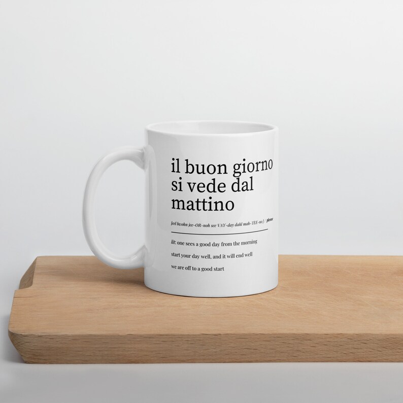 Puede incluir: Taza de cer&aacute;mica blanca con un dise&ntilde;o negro que dice "il buon giorno si vede dal mattino" en italiano, que se traduce como "un buen d&iacute;a se ve desde la ma&ntilde;ana". El texto tambi&eacute;n incluye la definici&oacute;n: "uno ve un buen d&iacute;a desde la ma&ntilde;ana comienza bien tu d&iacute;a, y terminar&aacute; bien vamos a un buen comienzo."