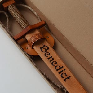Personalised wooden sword with engraved name in a cardboard gift box, leather sheath and rope strap included