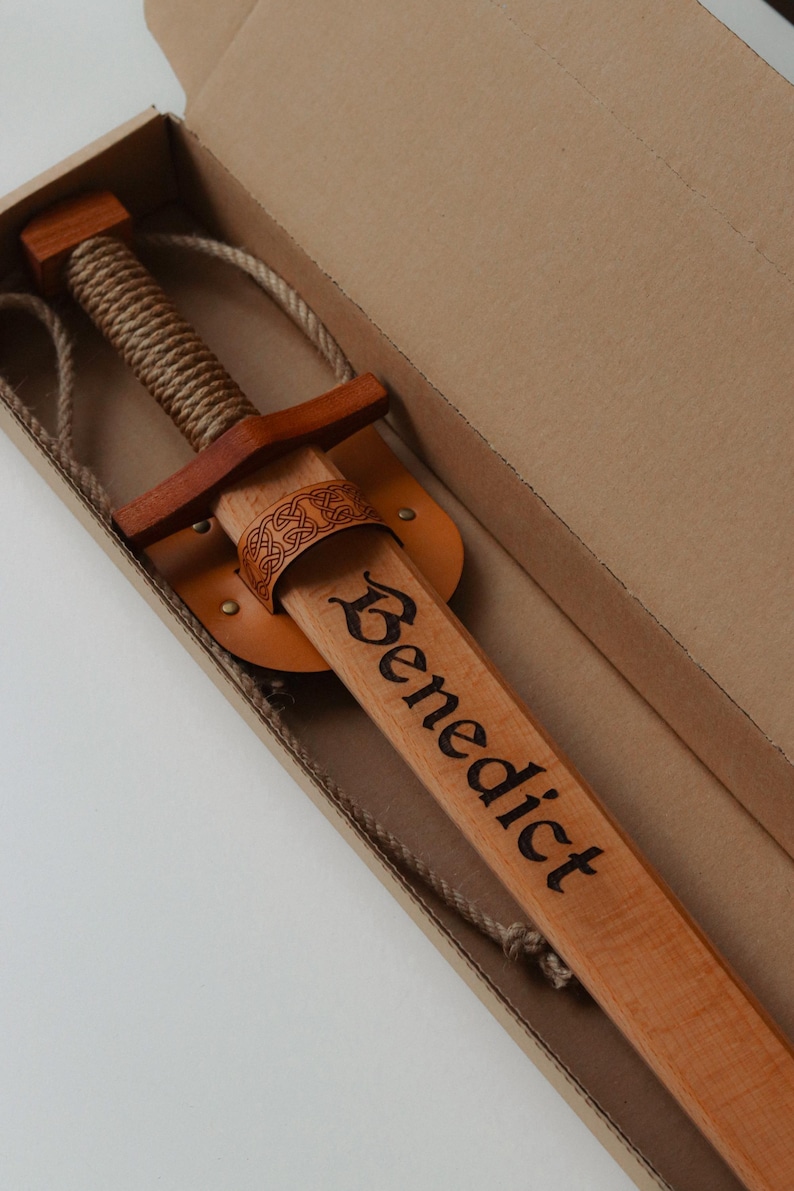 Personalised wooden sword with engraved name in a cardboard gift box, leather sheath and rope strap included