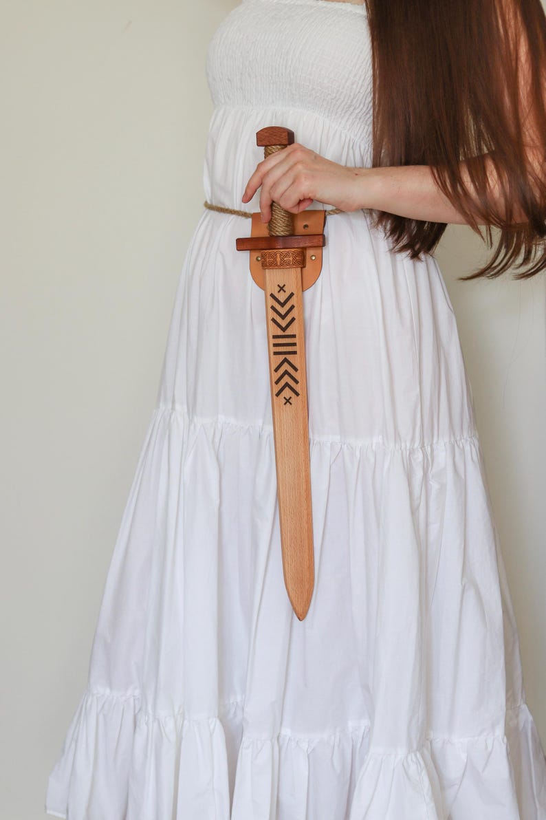 Wooden toy sword with engraved blade and leather sheath, worn on rope belt, medieval role play accessory
