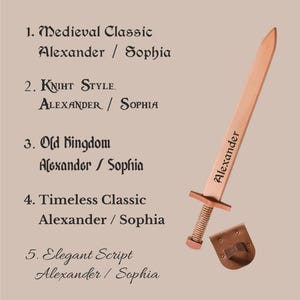 May include: A light-colored wooden toy sword with the name Alexander engraved on the blade, accompanied by a brown leather belt loop. The image displays a font selection guide with five options: Medieval Classic, Kniht Style, Old Kingdom, Timeless Classic, and Elegant Script, showing the names Alexander and Sophia as examples.